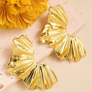 Detailed close-up of golden leaf-shaped earrings with fine radial texture and metallic gloss