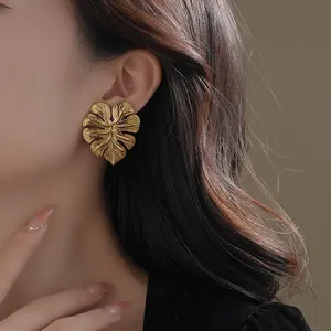 Elegant gold tropical leaf stud earrings featuring detailed vein texture and organic design
