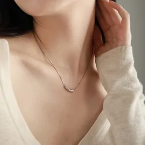 Détail d'un pendentif aubergine argenté courbé sur un collier minimaliste en titane