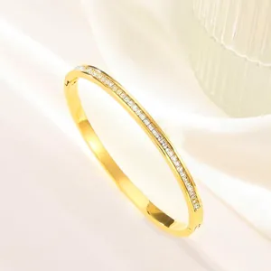Macro detail of gold plated bangle featuring a row of square zirconia with side hinge clasp