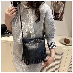 Détail d'un sac à bandoulière bohème noir à franges présenté dans un décor de style