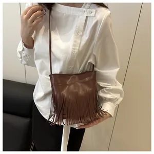 Détail d'un petit sac bandoulière marron vintage avec franges porté par un mannequin