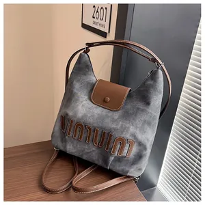 Detail der grauen Vintage-Tasche mit braunem Leder-Patch und weißen Kontrastnähten