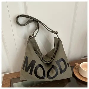 Dettaglio della borsa a tracolla in tela verde scuro con scritta MOOD e cinturino