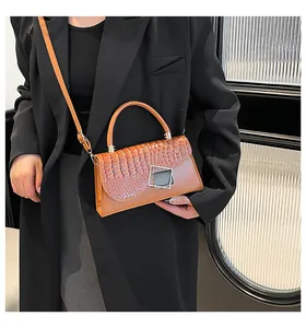 Dettaglio borsa marrone con texture coccodrillo e fibbia in argento su giacca nera elegante