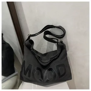 Dettaglio della borsa a tracolla in tela nera con scritta MOOD e tracolla regolabile