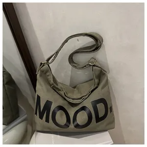 Dettaglio borsa a tracolla in tela verde militare con stampa di lettere MOOD. nere
