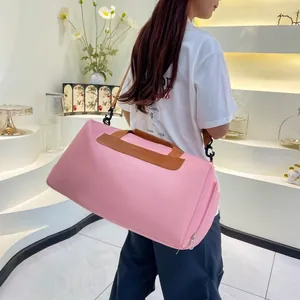Pink travel bag with leather handles shown worn by a model in a modern interior