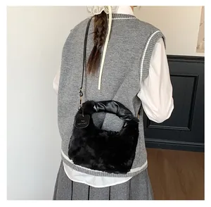 Detail einer Plüsch-Handtasche aus schwarzem Kunstpelz mit Ledergriff am Modell