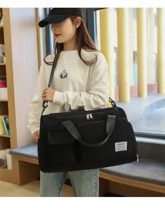 Close-up of black corduroy travel bag with front flap pockets and white logo label
