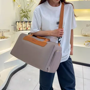 Fashionable travel bag in taupe with adjustable orange straps shown on a model