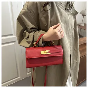 Vue détaillée du mini sac rouge texture litchi avec fermoir doré et bandoulière amovible