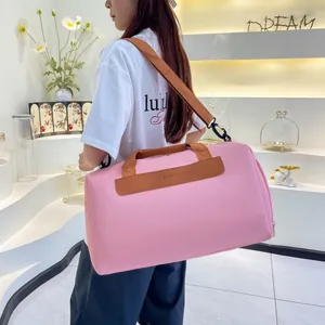 Pink travel bag detail featuring Fashion logo and brown woven handle on a gym duffle