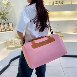 Pink travel bag detail featuring leather handles and adjustable shoulder strap with fashion logo