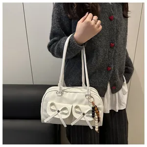 Close-up of white PU leather shoulder bag featuring bow pockets and bead pendant detail