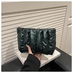 Detail view of a black quilted envelope clutch with high-gloss finish and puffy texture