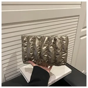 Detail of metallic pleated clutch bag held over books with focus on shimmering texture