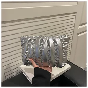 Detailed view of silver metallic quilted clutch bag with vertical padded stitching texture