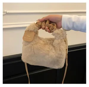 Nahaufnahme der beigen Plüsch-Handtasche mit gerafftem Griff und Marken-Tag-Detail