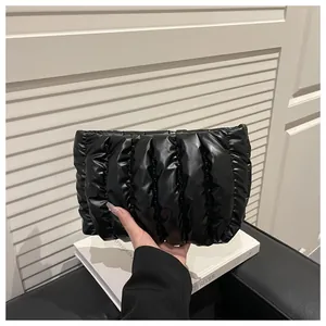 Close-up of black quilted cloud clutch bag with vertical pleats and padded soft texture