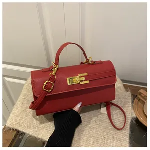 Détail du sac boîte rouge à grain de litchi avec fermoir doré sur tapis en peluche