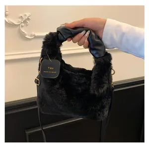 Detail einer Plüschtasche mit geriffeltem Ledergriff und graviertem Goldanhänger