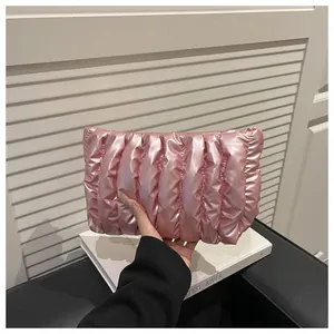 Detail of a metallic pink quilted clutch bag featuring vertical padded texture design