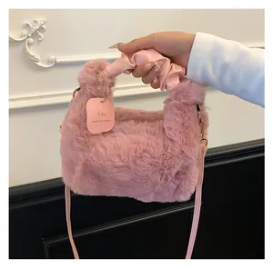 Detailaufnahme der rosa Plüschtextur und des Lederanhängers an einer modischen Handtasche