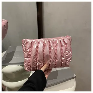Detail of pink quilted puffer clutch bag with metallic finish and zipper closure