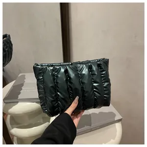 Close-up of black quilted puffer clutch bag with glossy finish and soft pleat design