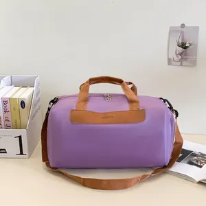 Detail of purple nylon fitness bag with brown leather handles and a fashion patch