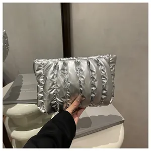 Detailed view of a silver metallic quilted clutch bag with glossy padded texture