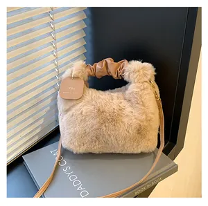 Detailansicht der beigen Plüschhandtasche mit gerafftem Griff und Markenanhänger