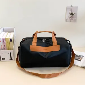 Detail of travel bag showing sturdy brown handles and a Fashion logo on black fabric