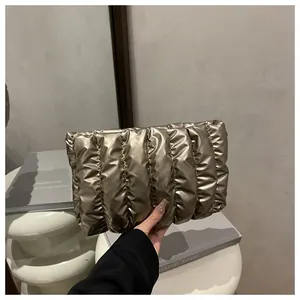 Detail of champagne gold quilted clutch bag with vertical puffy metallic texture