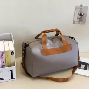 Detail of grey fitness travel bag with brown straps and metallic double zipper design