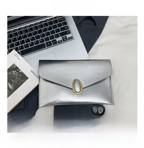 Close-up of silver envelope clutch bag with brushed metal texture and golden oval clasp
