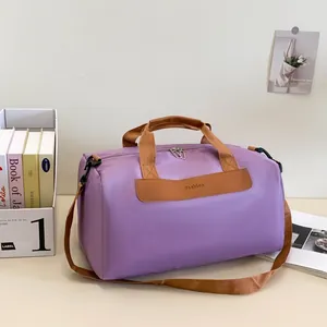 Detail view of purple travel bag featuring leather handles and adjustable shoulder strap