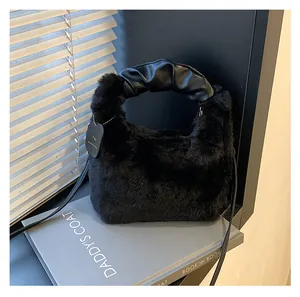 Detail einer schwarzen Plüsch-Handtasche mit gerafftem Ledergriff und dünnem Schultergurt