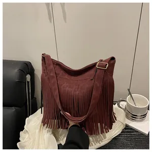 Close-up of deep red fringe tote bag with gold metal buckle and suede texture