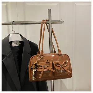 Close-up of brown glossy leather handbag with bow pockets and colorful bead charm