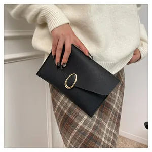 Detail of elegant black envelope clutch bag with gold clasp held by a model