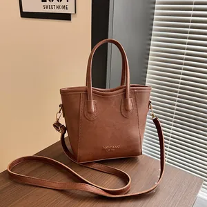 Vintage brown leather tote bag for women with gold lettering on a wooden table