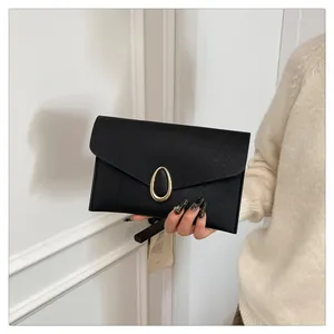 Close-up of black Saffiano leather envelope clutch bag with oval gold clasp buckle