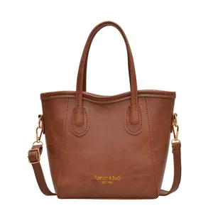 Vintage brown leather tote bag with gold lettering and adjustable shoulder strap