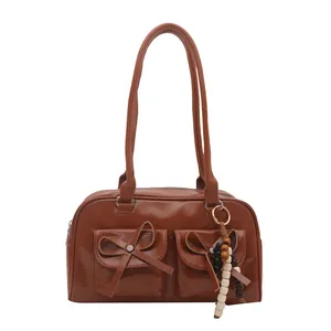 Brown glossy leather underarm bag with front bow pockets and wooden bead charm