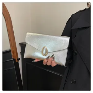 Macro shot of silver envelope clutch bag with elegant golden oval metallic buckle