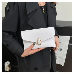 Detail of white envelope clutch bag with gold oval lock on textured leather