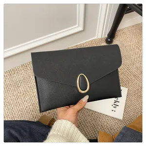 Close-up of black Saffiano leather envelope clutch featuring a gold oval metal buckle