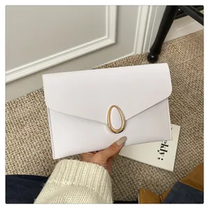 Detail of white envelope clutch with cross-grain texture and gold oval metal clasp
